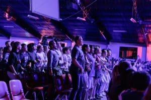 A large crowd of young people at KYCK 2026, participating in indoor worship, standing, singing, and enjoying Christian youth conference.