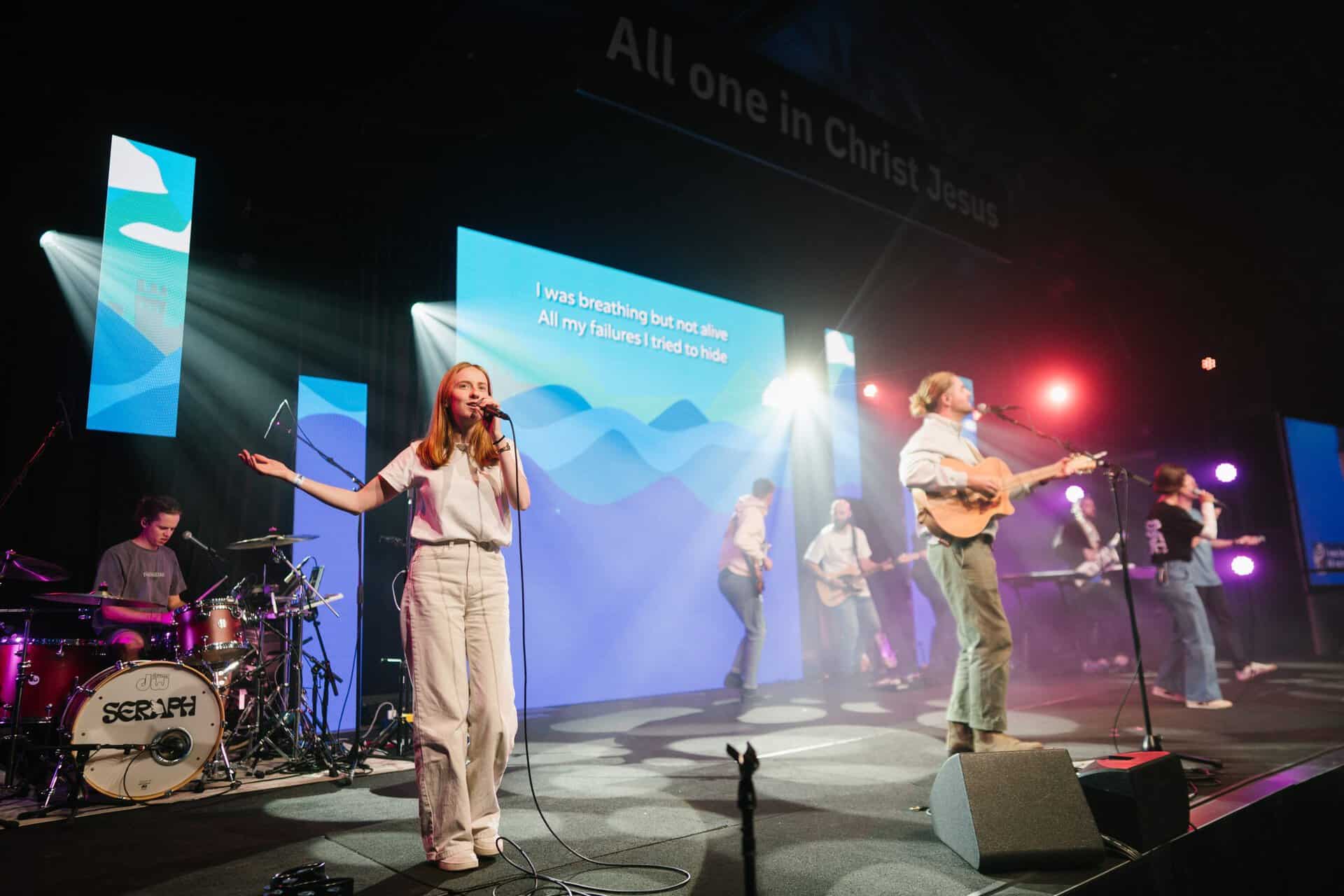 Youth worship band performing live at KYCK 2026 youth Christian event, with musicians and singers on stage under vibrant lighting.