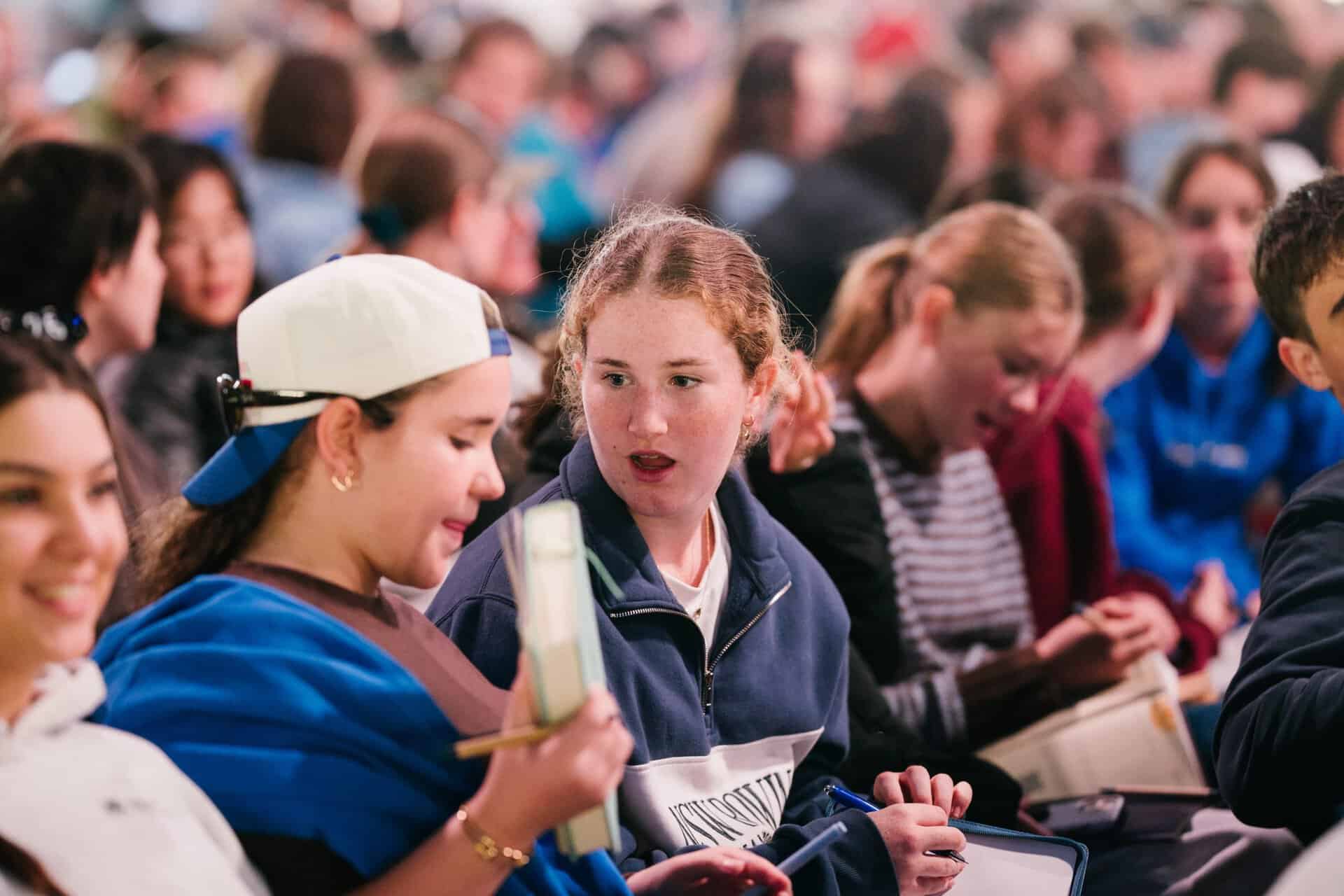 Group of young people attending KYCK 2026 youth conference, engaging in discussions and activities, with a diverse crowd of teenagers in a large indoor event.