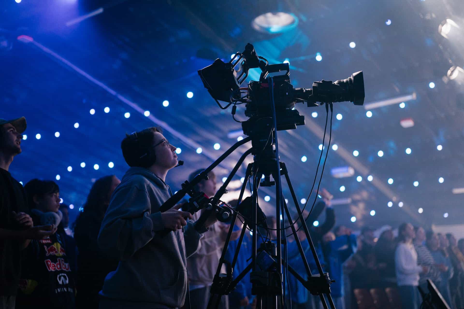 Young videographer filming at KYCK 2026 youth conference with professional camera in a vibrant, illuminated event setting.