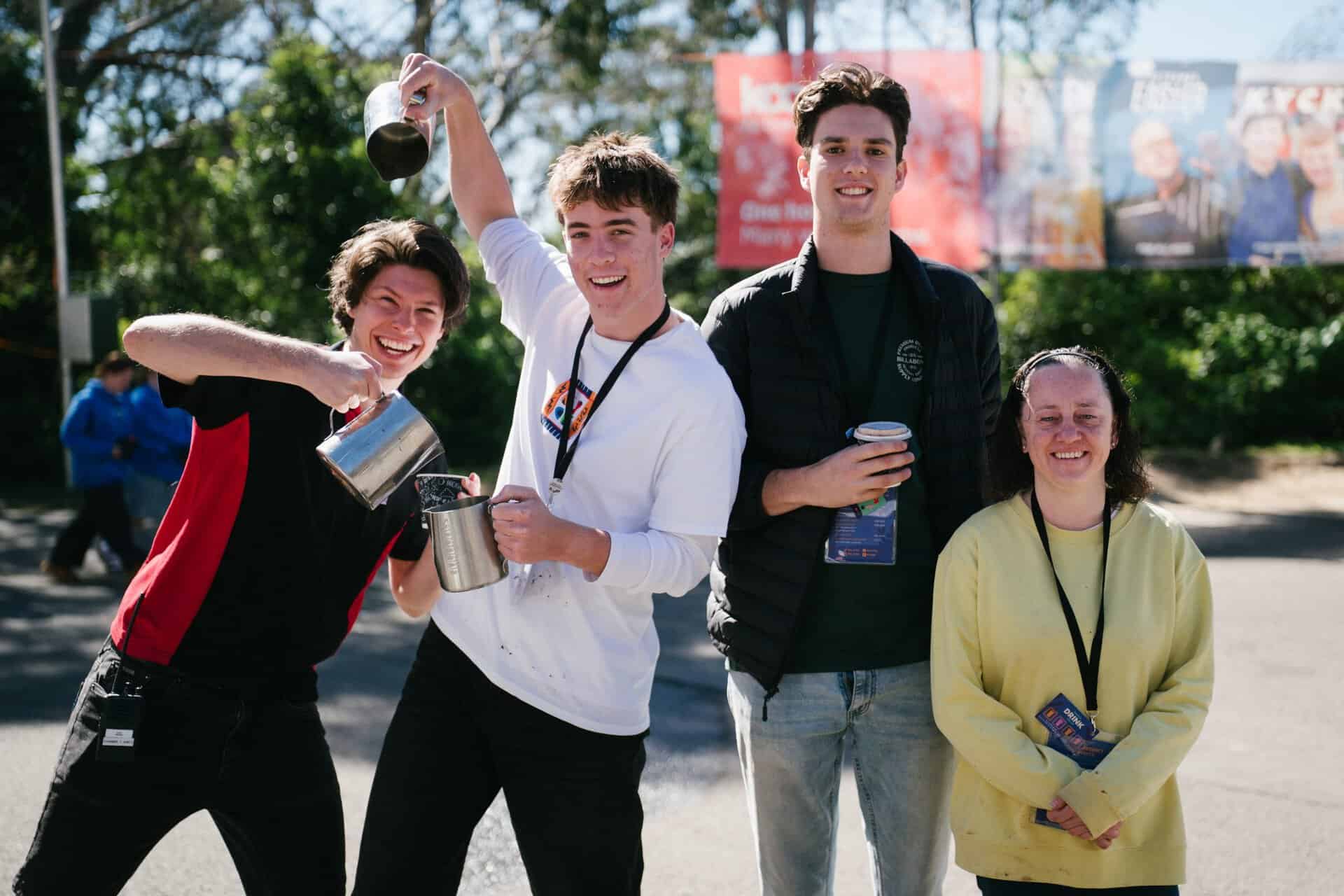 Group of four young people smiling and enjoying KYCK 2026 youth event outdoors, with one pouring water, showcasing fun and community spirit.
