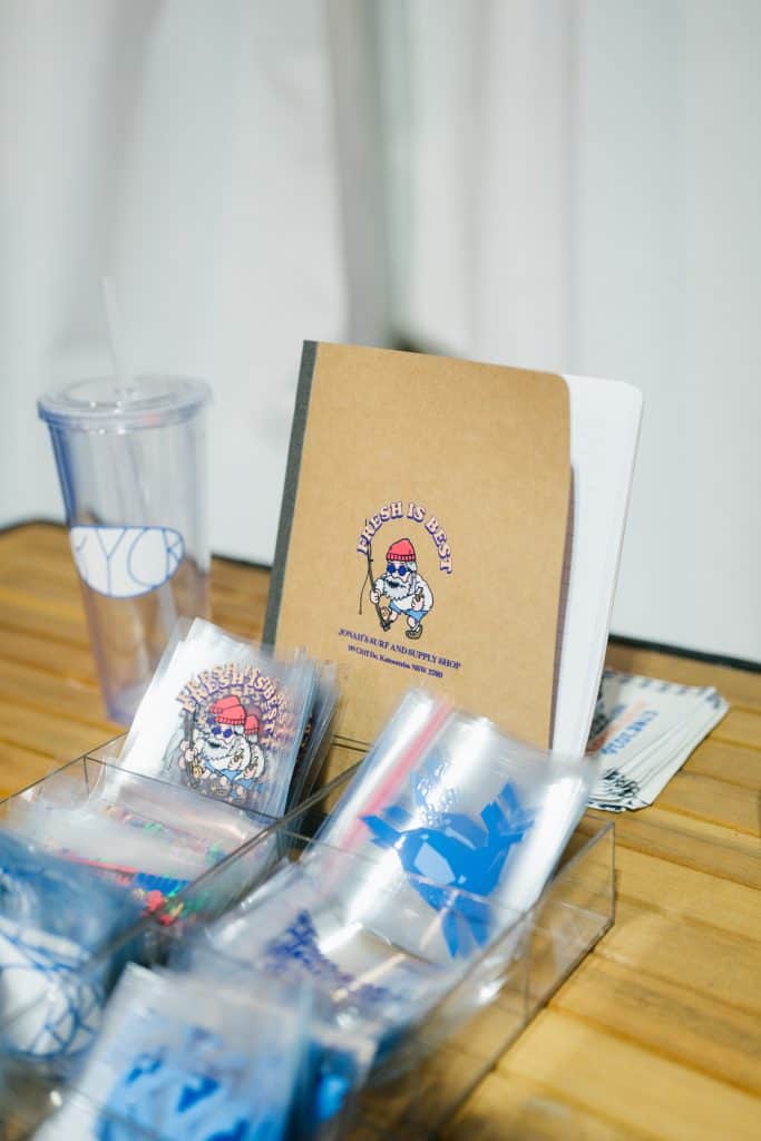 KYCK 2026 event materials including notebooks, merchandise, and promotional items displayed on a wooden table.
