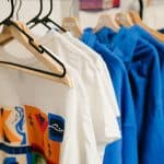 T-shirts in white and blue hanging on a rack, promoting KYCK 2026 youth event merchandise.