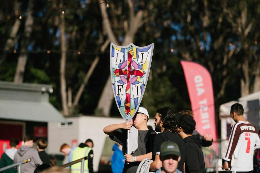 Youth group holding a KYCK 2026 banner at a Christian youth event outdoors, with trees and event tents in the background.