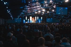 Large audience attending KYCK 2026 youth conference with stage and speakers under decorative lighting.